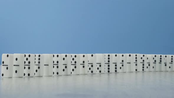 Domino Effect - a Series of Dominoes Falling Down the Chain on Blue Background alt