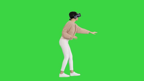 Cute Young Woman Walking and Using Interactive VR Headset on a Green Screen, Chroma Key. alt