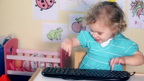 Emotional Toddler Girl Playing with Computer Keyboard on Her Little Table