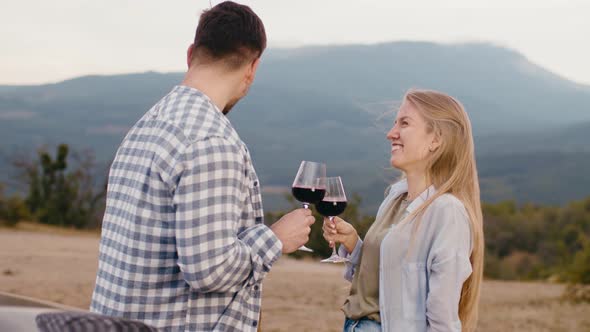 Young Couple Flirting and Tasting Wine at Countryside Against Mountains