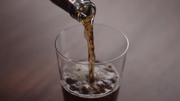Slow Motion Man Pour Cola Into Tumbler Glass on Walnut Table with Copy Space