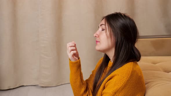 Long Haired Young Brunette in Sweater Looks at Manicure alt