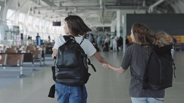 Happy Lesbians Holding Hands and Running at Airport alt