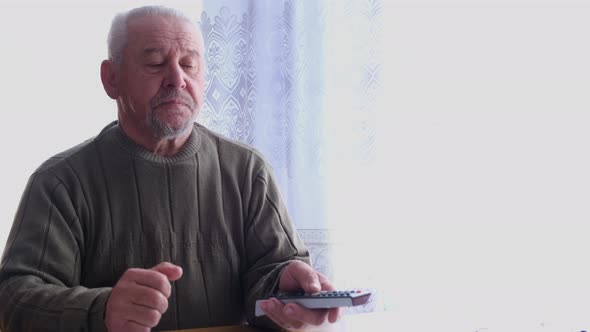 An Old Man Switches TV Channels with a Remote Control alt