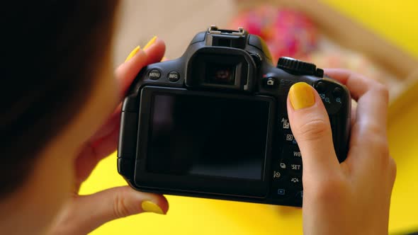Woman's Hands Take Pictures with Photo Camera of Delicious Donuts in Box alt