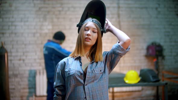 Young Sexy Woman Standing in the Workshop and Playing with a Helmet alt