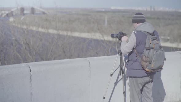 Man Male Cameraman Photographer with a Camera DSLR on a Tripod in the City Shoots Video Photo . Kyiv alt