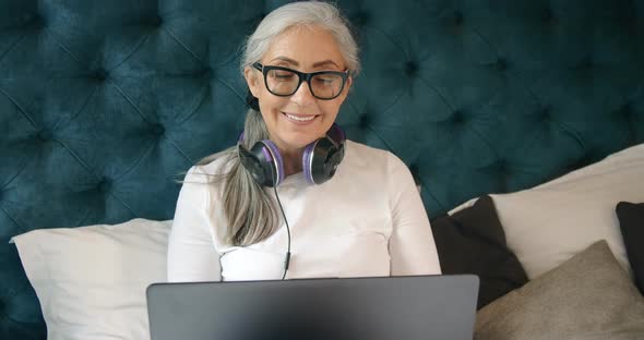 Elderly Woman with Laptop in Bedroom