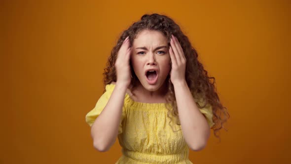 Young Curly Woman Disappointed and Shocked with Bad News Yellow Background