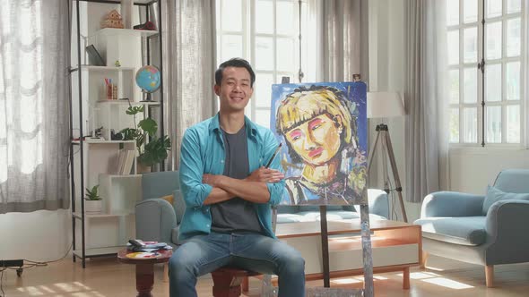 Asian Artist Man Holding Paintbrush Wipe The Sweat Before Crossing His Arms And Smiling alt