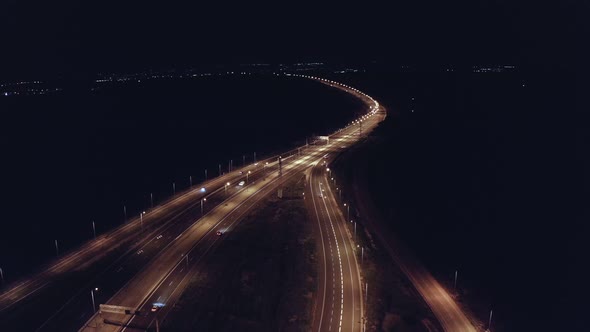 Drone aerial shot of night traffic on a highway showing cars and lanes of light with bridges