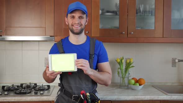Plumber Holds a Digital Tablet with a Green Screen in the Kitchen alt