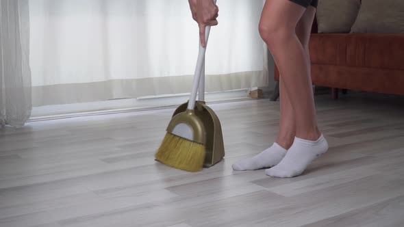 A Woman Sweeps the Floor in an Apartment