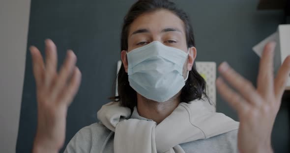 Portrait of Guy Wearing Face Mask Making Video Call in Office Talking and Looking at Camera alt
