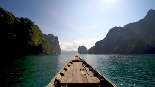 Travel lake landscape on wooden longtail boat on a tropical limestone cliff exploring Khao Sok Lake alt