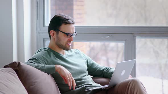 Young attractive man holding video conference remotely from home office alt