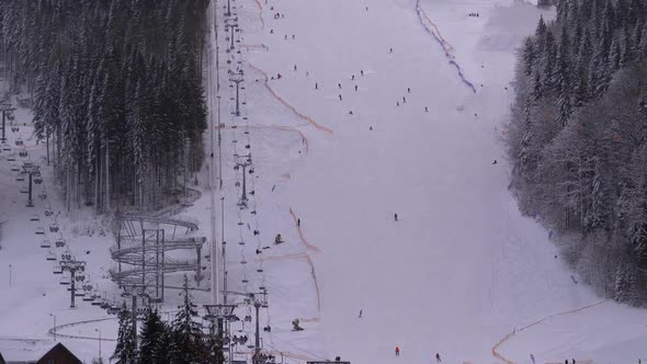 Skiers and Snowboarders Ride on a Snowy Slope at a Ski Resort in Sunny Day alt