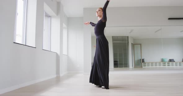 Caucasian female ballet dancer practicing ballet during a dance class in a bright studio alt