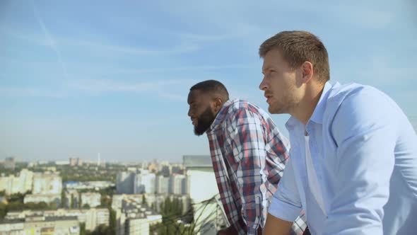 Male Friends Talking Standing Outdoor Terrace, Enjoying Work Break on Balcony