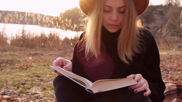 Millennial Woman Slow Motion Caucasian Blonde Woman with Beige Hat in Black Sweater Reads Book in alt