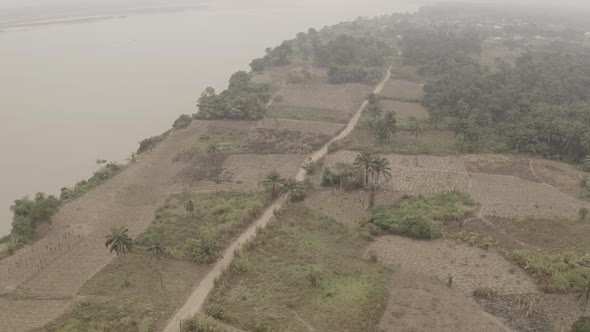 Aerial shot of coastal farmland near River Niger revealing a narrow road  to the community alt