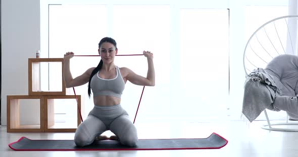 Woman doing exercises with resistance bands at room.