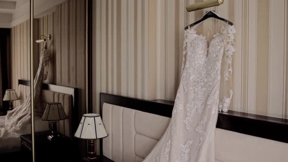 the bride's wedding dress is hanging in the room on the bed