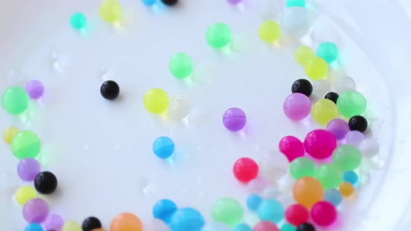 Orbiz rotate and pours on a white background. Decoration of water balls with hydrogel - orbeez.