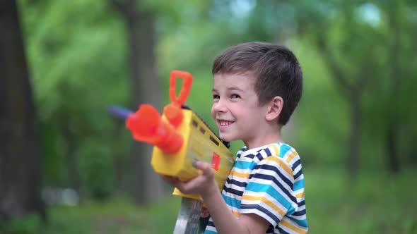 Child Boy Shoots From Toy Weapons Gun Outdoors