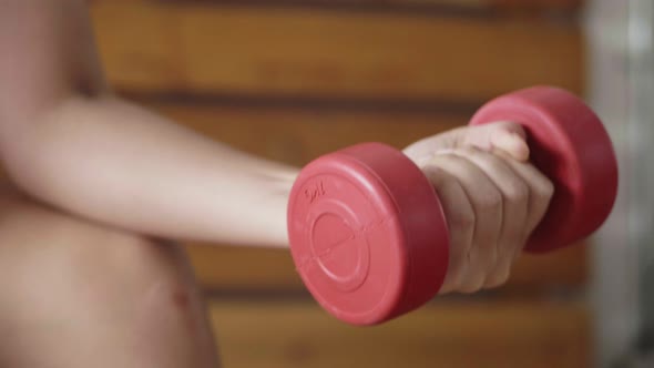 Asian sportswoman practicing exercises with a dumbbell in the fitness gym.