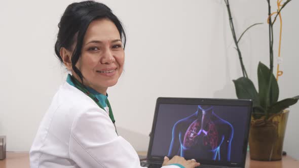 Mature Female Doctor Examining Lungs Scan on Her Laptop at the Clinic alt