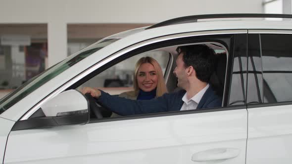 Portrait of Joyful Man with His Wife Sitting at Wheel of a Car and Showing Keys to a New Car From alt