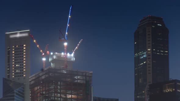 Aerial view of skyscrapers under construction with huge cranes timelapse.