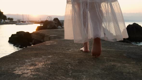 Closeup Female Feet Walking Along the Pier at the Sunset or Sunrise alt