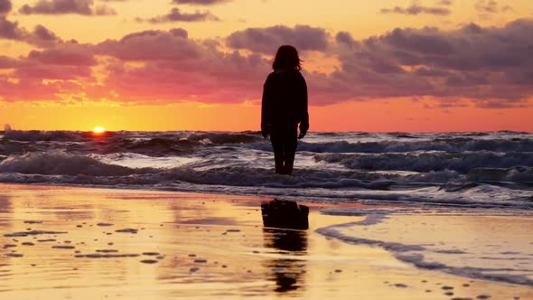 Silhouettes of Two Young Girls Watching Sunset on Beach.