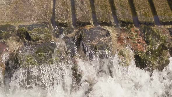 Slow motion. Small waterfall in urban park during Autumn. alt