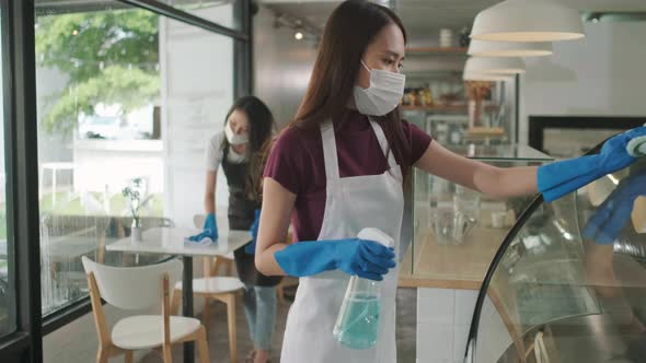 Waitress wearing face mask cleaning table disinfectant spray in in coffee shop restaurant