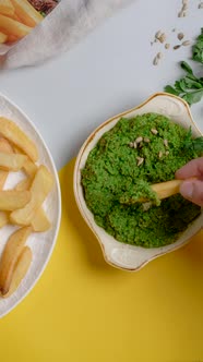 Vertical Tabletop Video Man Scoops Up Pesto Sauce with Crispy Potato Wedges