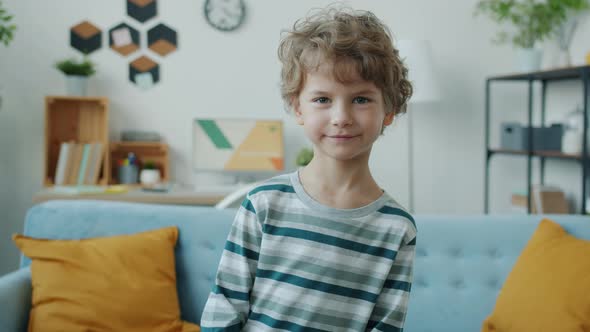 Slow Motion Portrait of Cute Little Boy Smiling Laughing Looking at Camera Indoors at Home alt