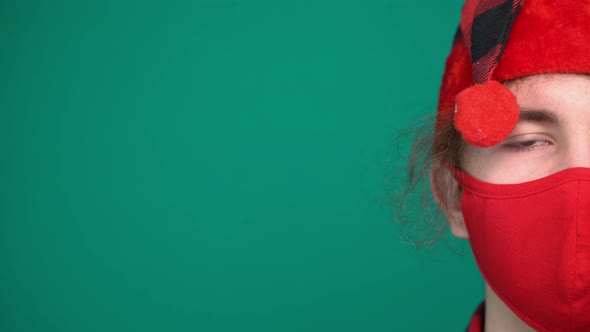 Portrait of Boy in Santa Hat Wears a Red Medical Mask Looking at Camera alt
