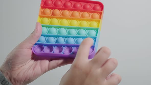 Kid Playing Pushing Bubbles on Trendy Rainbow Poppit Fidget Toy with Fingers alt