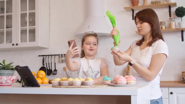 Mother and Daughter Icing Cupcakes and Having Video Call