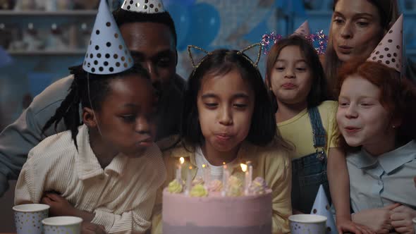 Crop View of Multi Ethnic Children and Adults Blowing Candles on Cake All Together alt