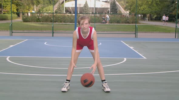 Young Girl Playing Basketball Outdoors Practicing Ball Handling Skill. A Tall Girl Basketball Player alt