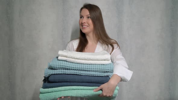 A Young Housewife Woman Holds a Stack of Fresh Washed Clean Linen in Her Hands