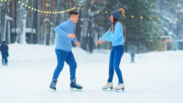 Guy in Sweater Tries To Amaze Girl on Outdoor Ice Rink