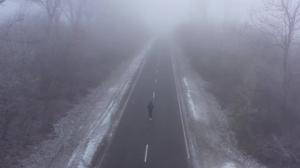 Sporty Man in Tracksuit Runs Along Road Surrounded By Frost Trees in Winter in Foggy Weather alt