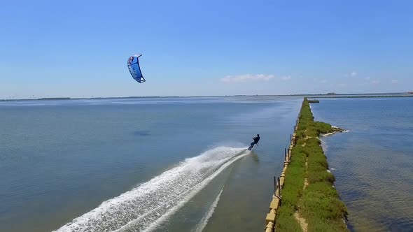 Aerial drone view of a man kiteboarding on a kite board. alt