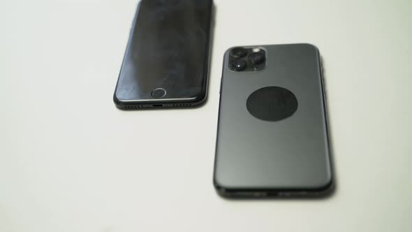 close up video of two dark smartphone on a white table alt