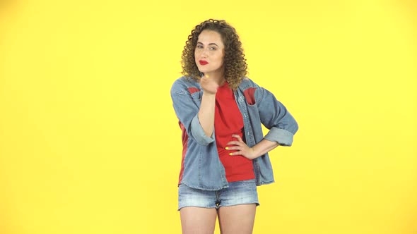 Girl Listens Carefully, Threatens with a Finger and Waves Her Head Negatively on Yellow Background alt